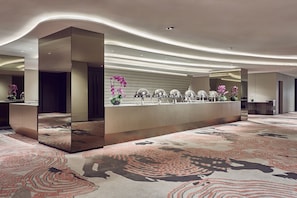 Welcome to our hotel lobby, featuring a sleek reception desk, large mirror, and patterned carpet.