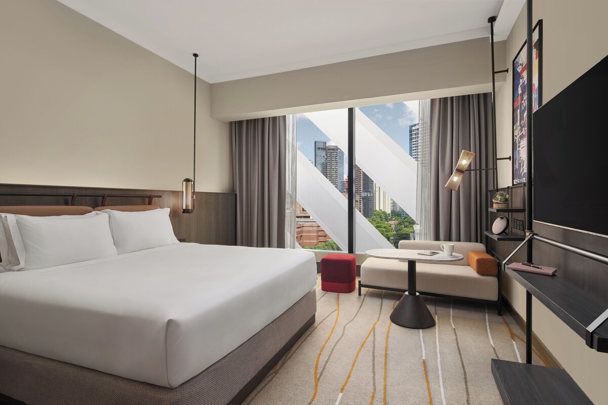 Una habitación de hotel con una cama grande, un sofá, una mesita y un televisor.