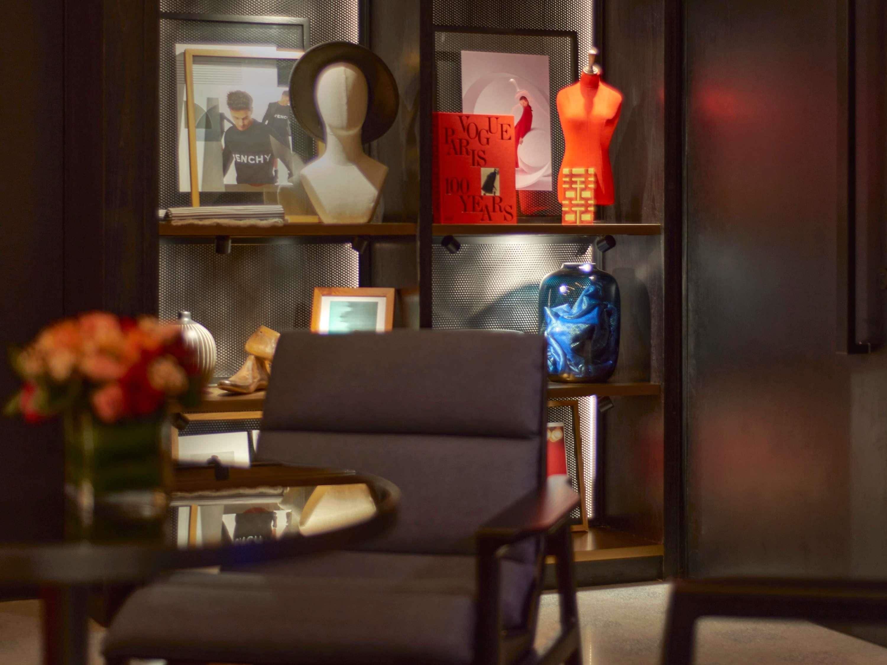 Ein modernes Interieur mit einer Couch, einem Blumenstrauß, einem gerahmten Bild und einer Mannequin.