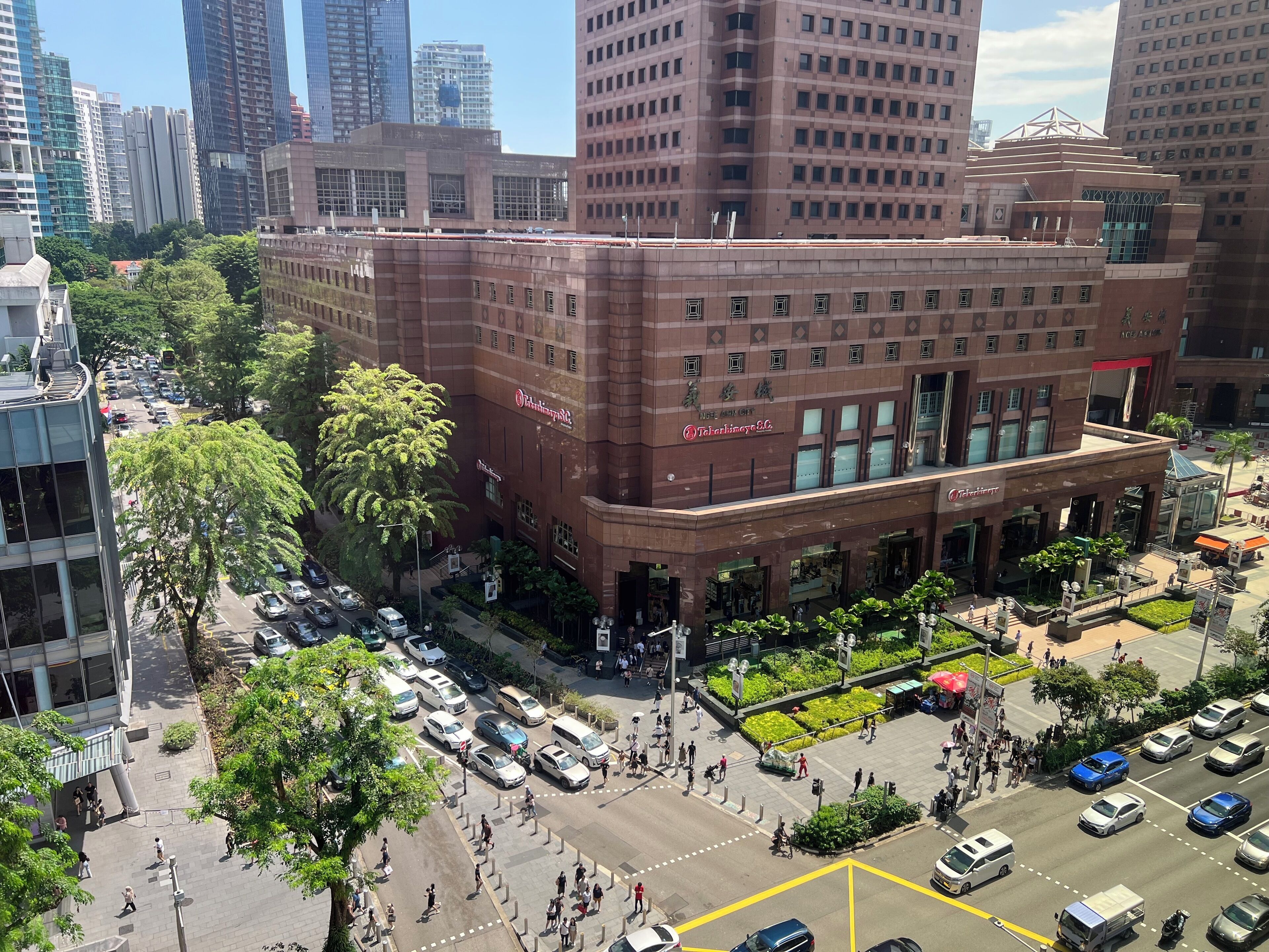 Un edificio de varios pisos con una entrada destacada, rodeado de coches aparcados y peatones.