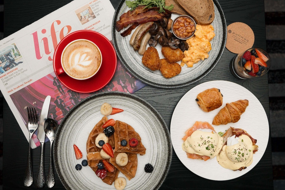 A breakfast setting with a newspaper, plates of food, and cutlery.