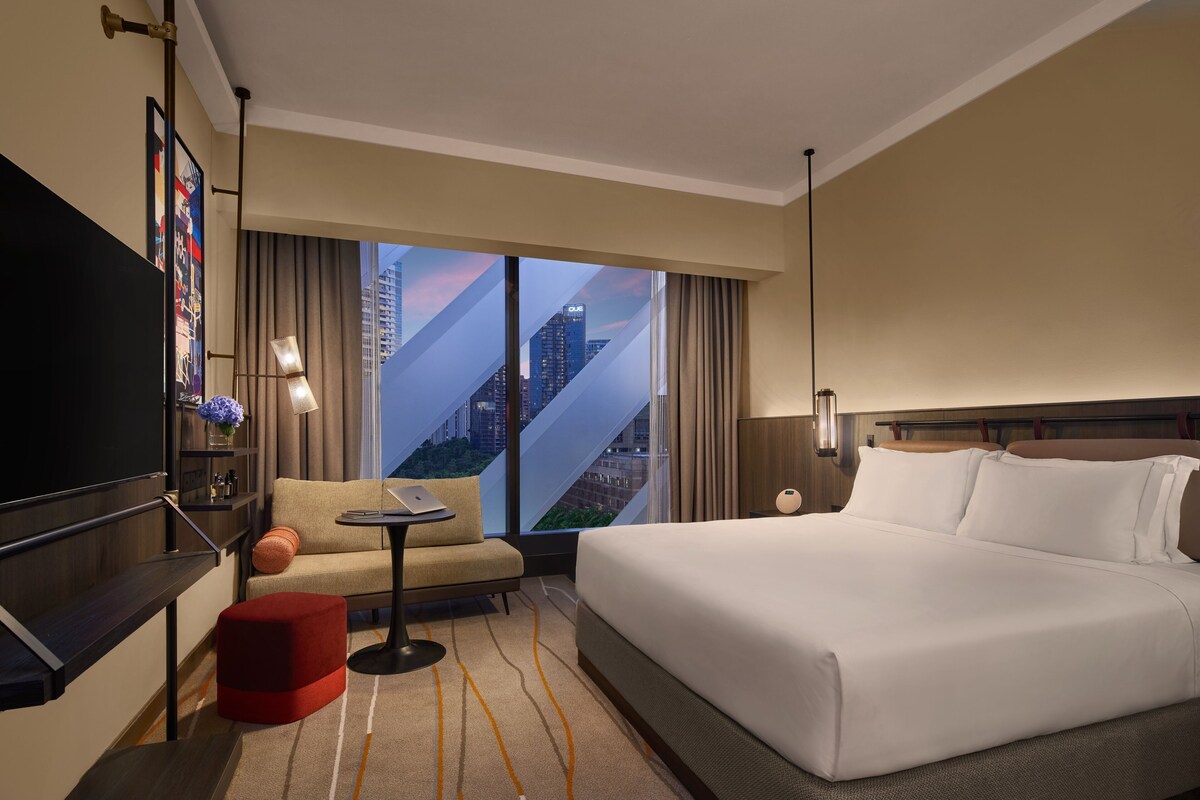 Una habitación de hotel con una cama grande, un sofá, una mesita y un televisor.
