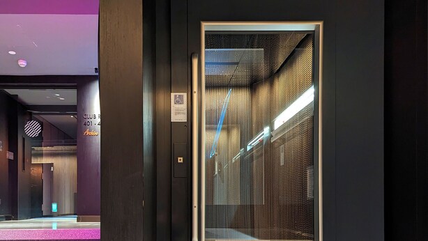 An elevator with a metallic interior and a glass panel.
