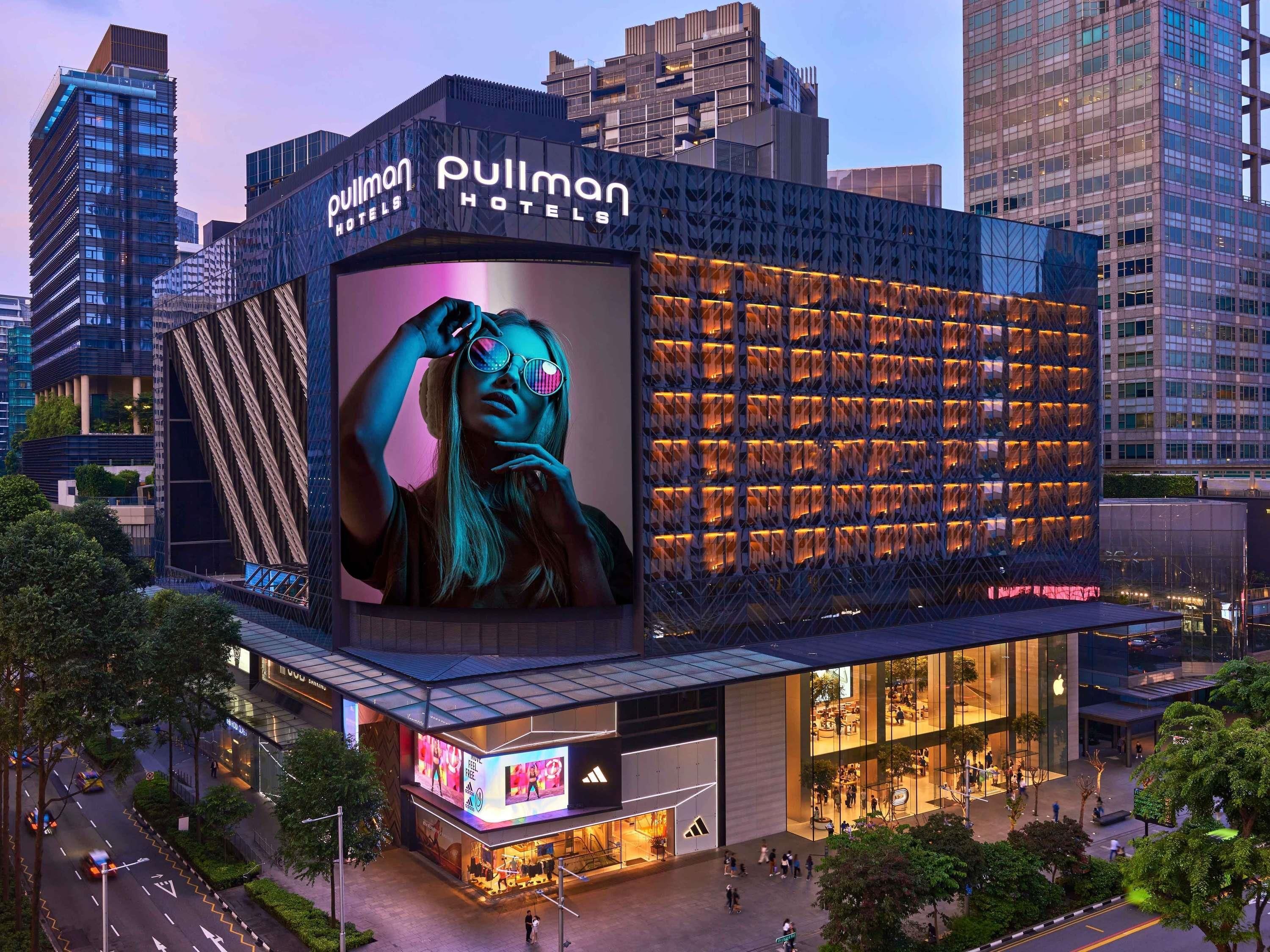 Un hotel con un gran cartel, fachada de vidrio y diseño arquitectónico moderno.