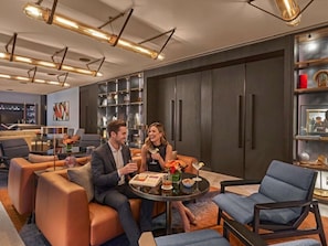 A modern hotel lobby with leather seating, a round table with drinks, and a large bookshelf. - Pullman Singapore Orchard  (Singapore)