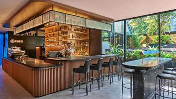 A modern bar area with a bartender, bar counter, seating, and shelves of bottles.