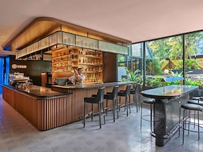 Un espace bar moderne avec un barman, un comptoir, des sièges et des étagères remplies de bouteilles.