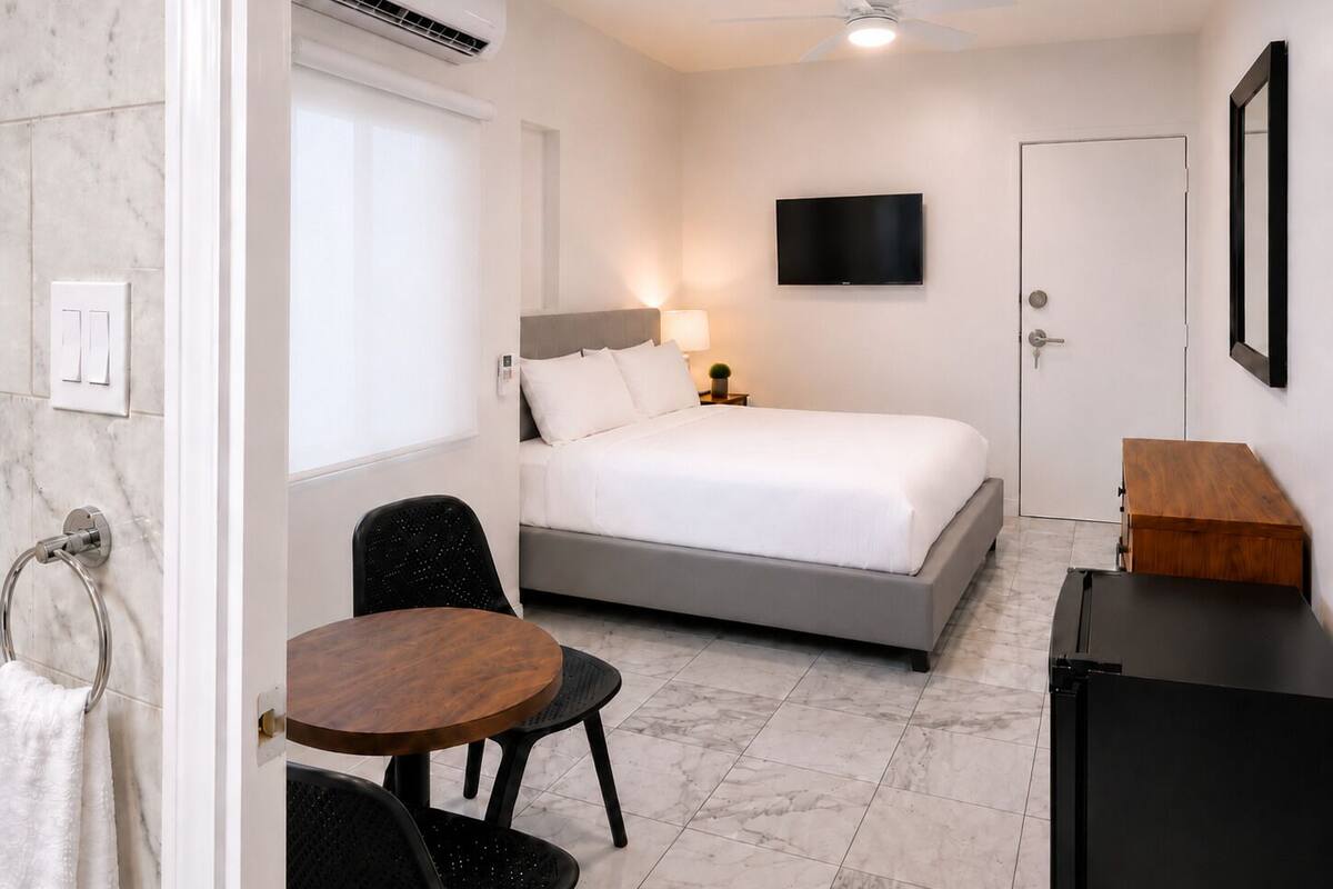 A bedroom with a bed, a TV, a desk, and a chair.
