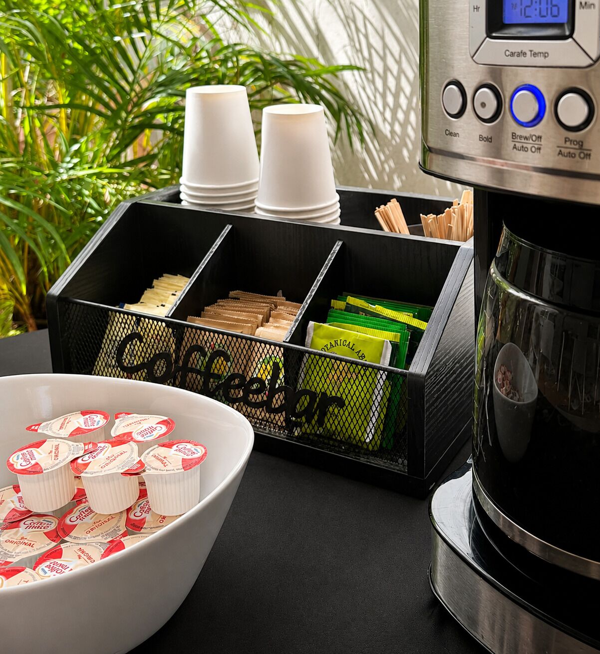 A coffee station with a coffee maker, cups, and coffee pods.