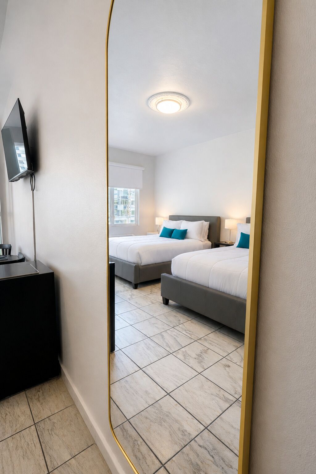 Habitación de hotel con dos camas, televisión y ventana.