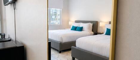Habitación de hotel con dos camas, televisión y ventana.