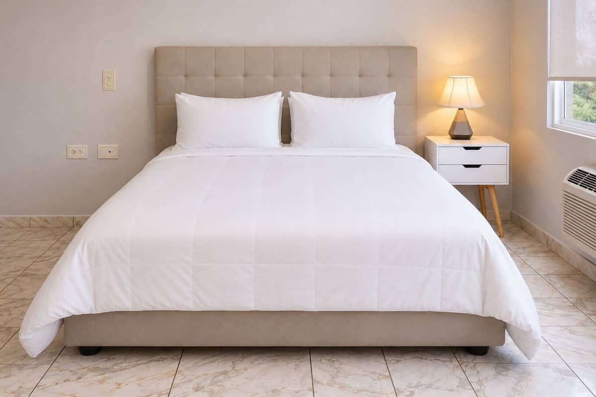 A bed with a headboard, two bedside tables, a lamp, and a window.