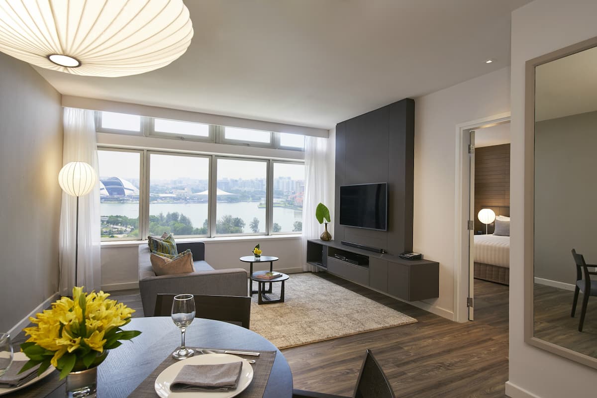 Ein modernes Wohnzimmer mit Essbereich, großen Fenstern und Blick auf die Stadt, einem Flachbildfernseher und einer gemütlichen Sitzecke.