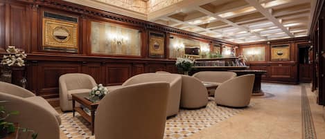 A spacious lobby with a checkered floor, plush seating, and ornate wall decorations.