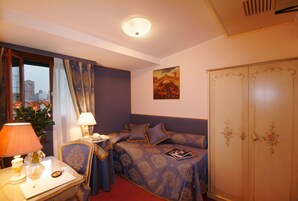 A hotel room with a bed, bedside table, lamp, and a wardrobe.