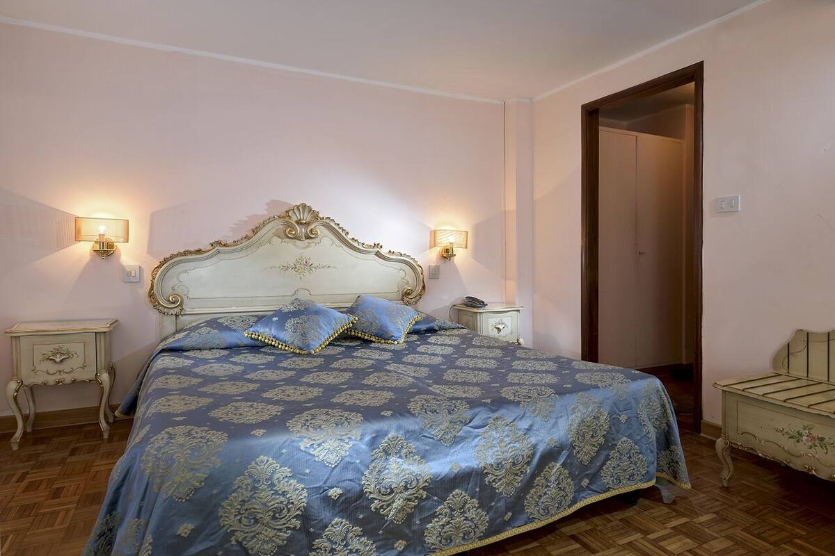 A bedroom with a large bed, two bedside tables, and a door.