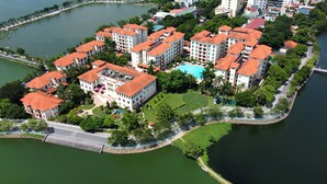 Vista aérea de una zona residencial con varios edificios, una piscina y un puente que conecta con una masa de agua.