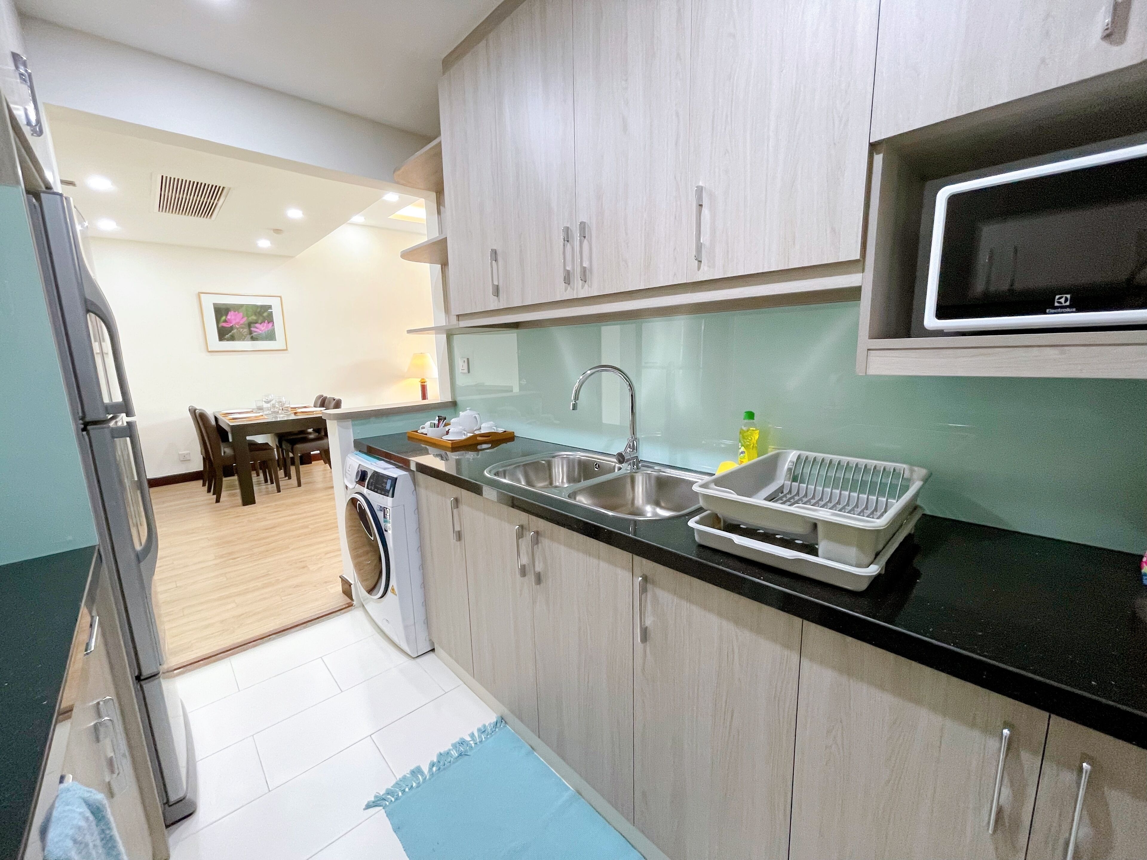 A compact kitchen with a washing machine, a microwave, and a sink.