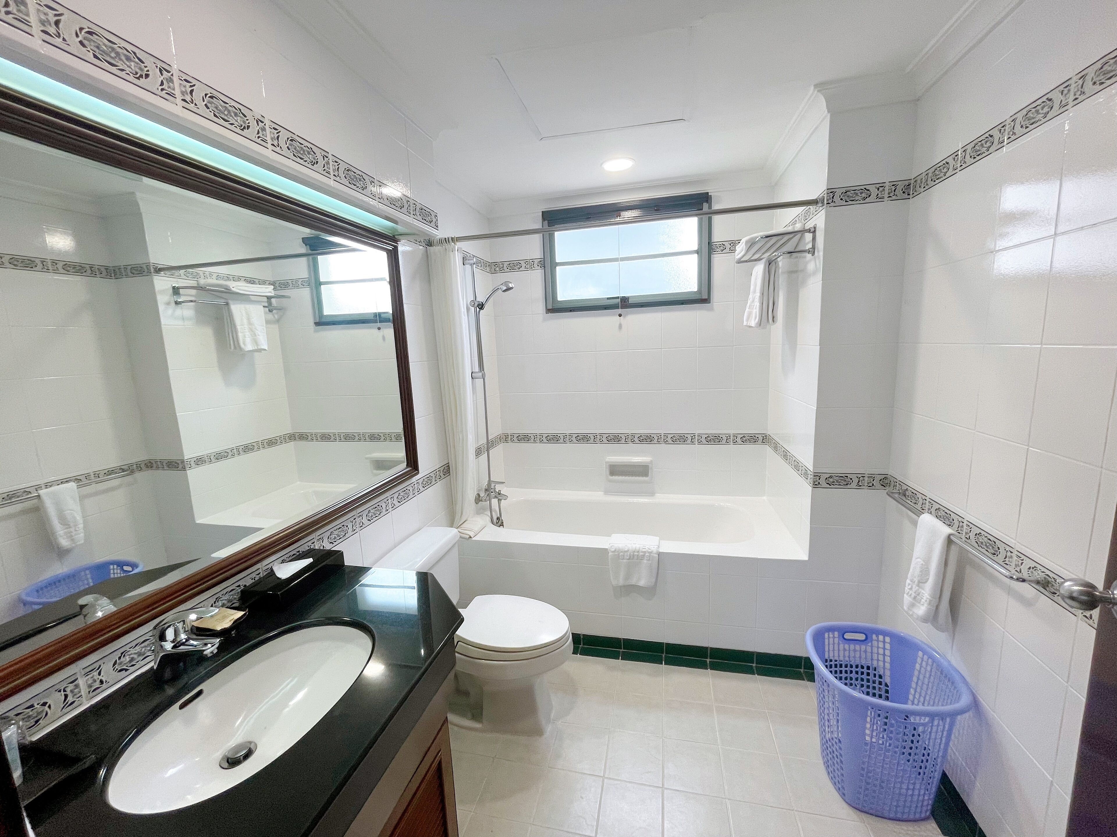A bathroom with a bathtub, toilet, sink, and a large mirror.