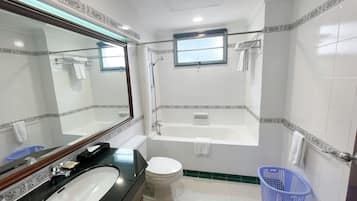A bathroom with a bathtub, toilet, sink, and a large mirror.
