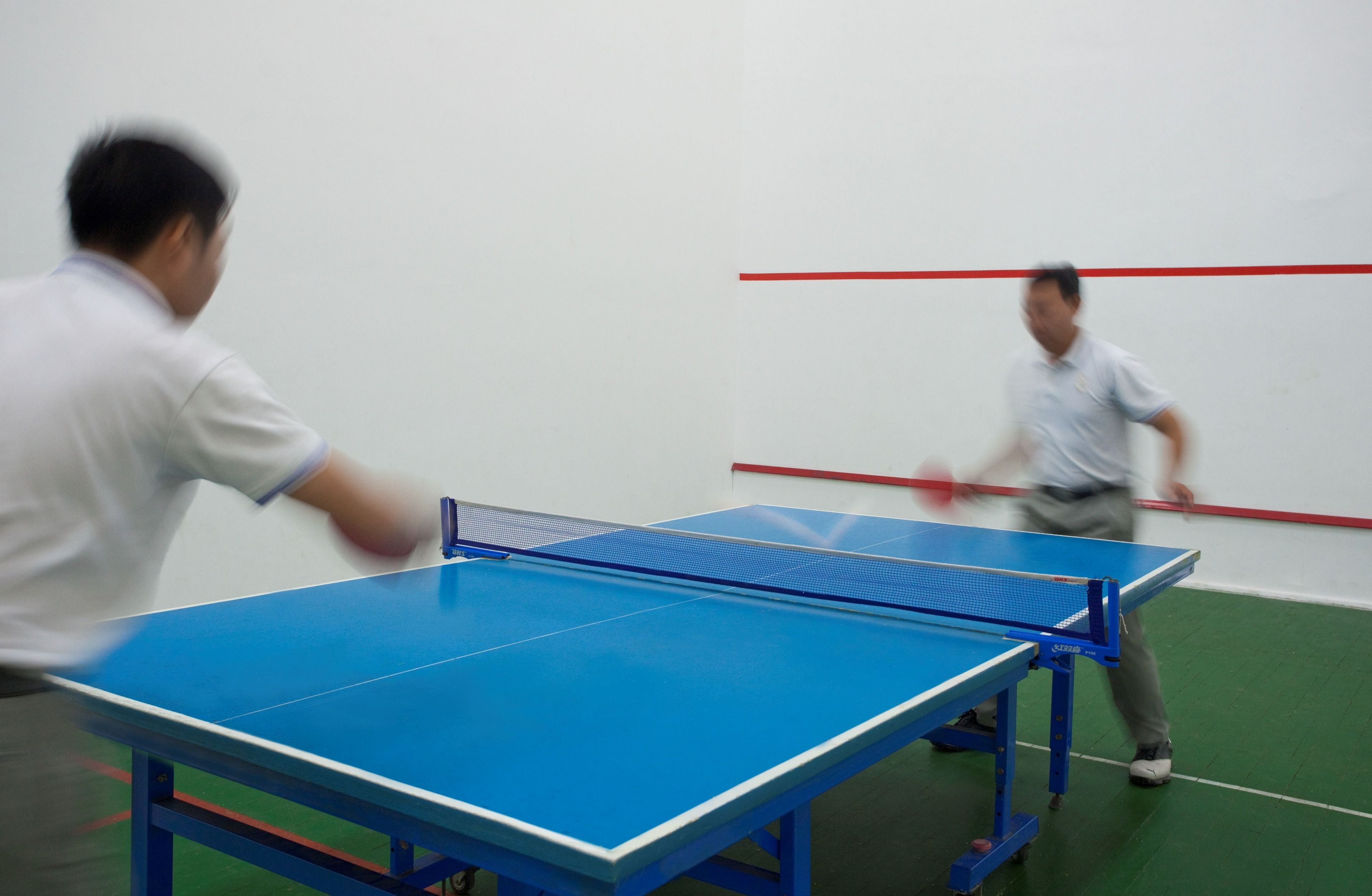 A table tennis table with two players in motion.