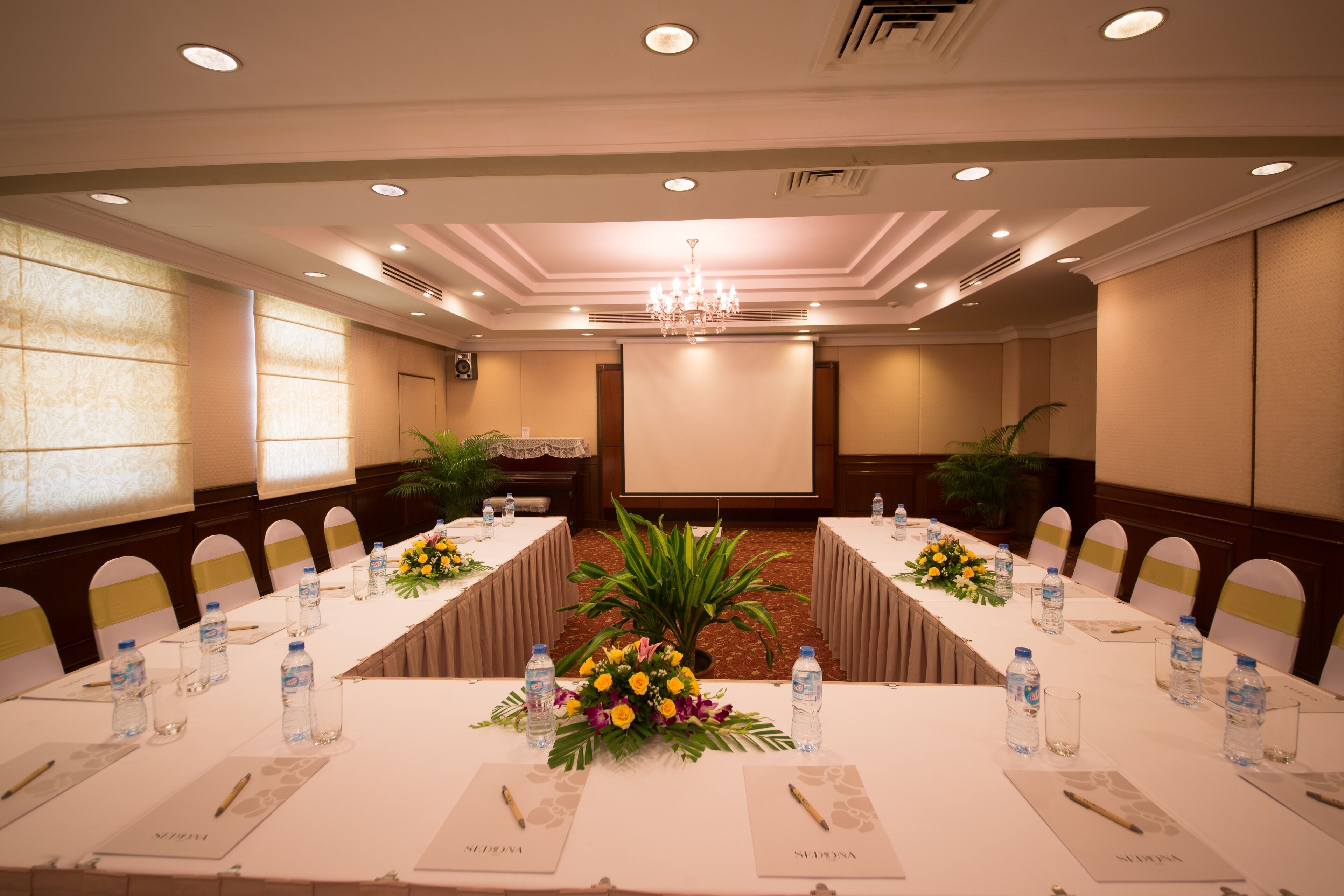 A conference room with long tables, water bottles, name cards, and floral centerpieces.
