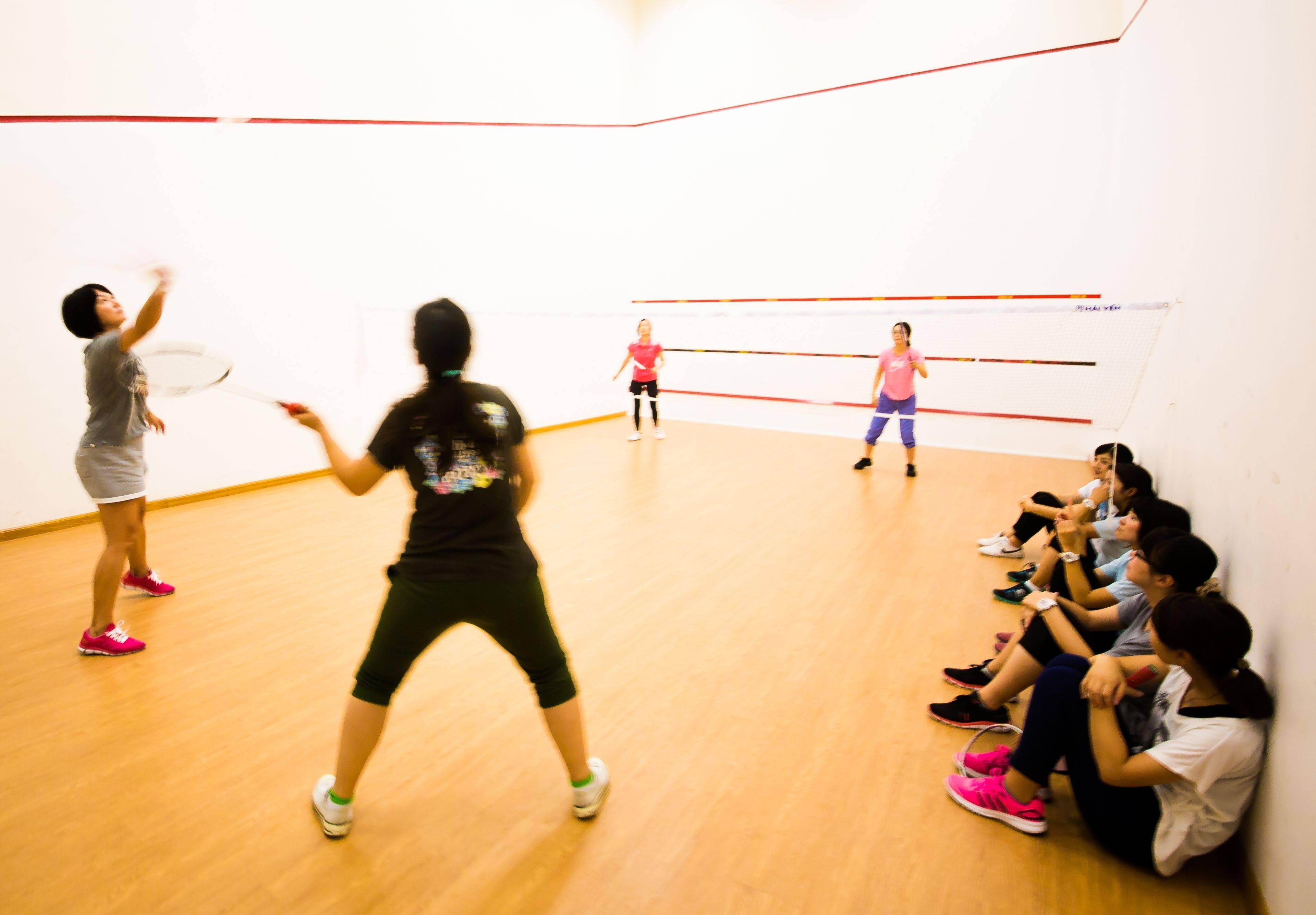 A squash court with players and spectators.
