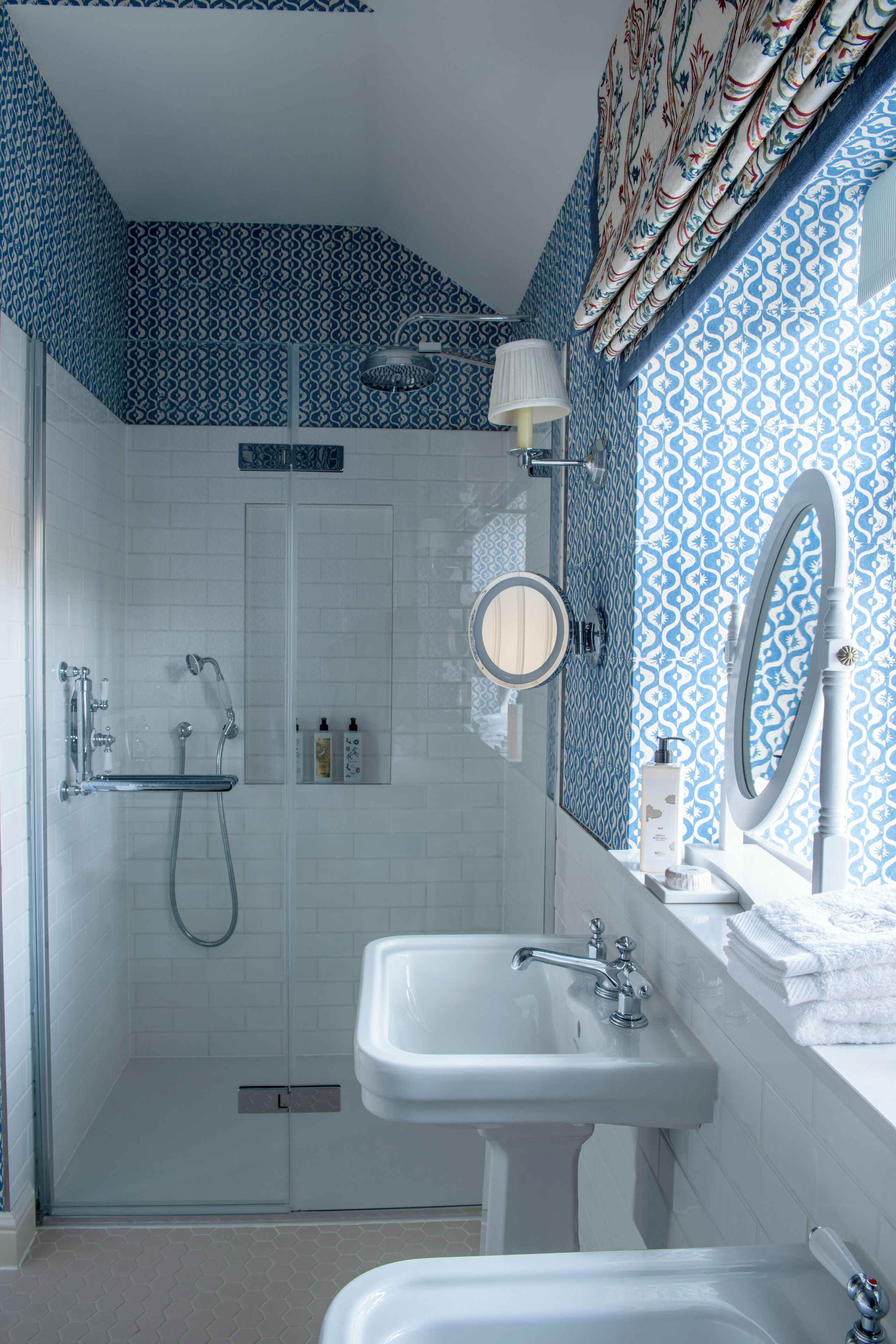 Un baño con ducha de vidrio, un lavabo blanco y un espejo.