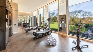 Un gimnasio moderno en casa con equipo de ejercicio, ventanas amplias y vistas al exterior.
