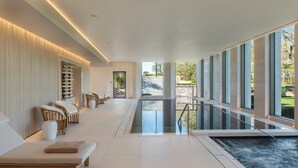 Un área de spa con sillones de descanso, jacuzzi y ventanas amplias con vistas al exterior.