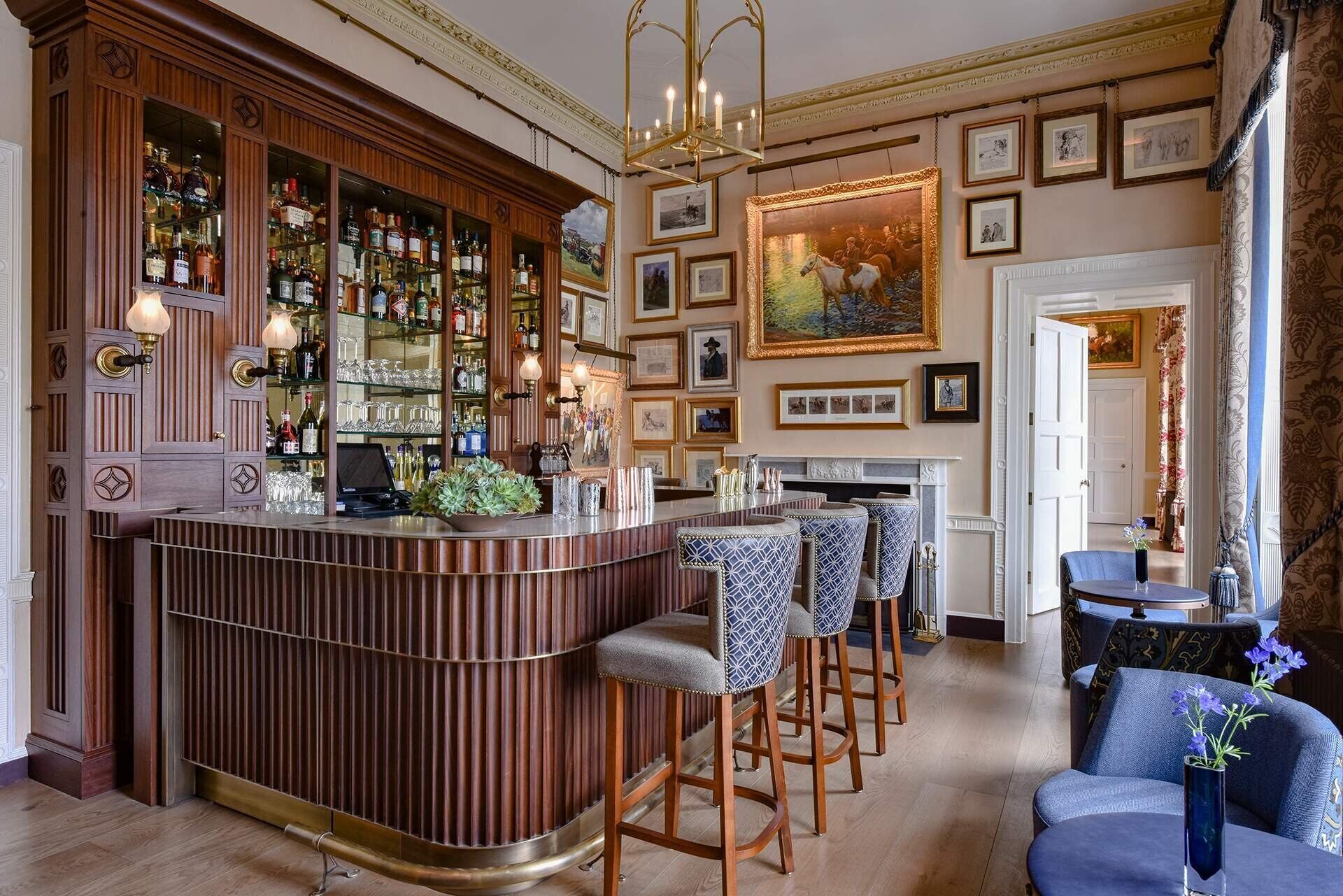 A bar area with a wooden counter, bar stools, and a fireplace.