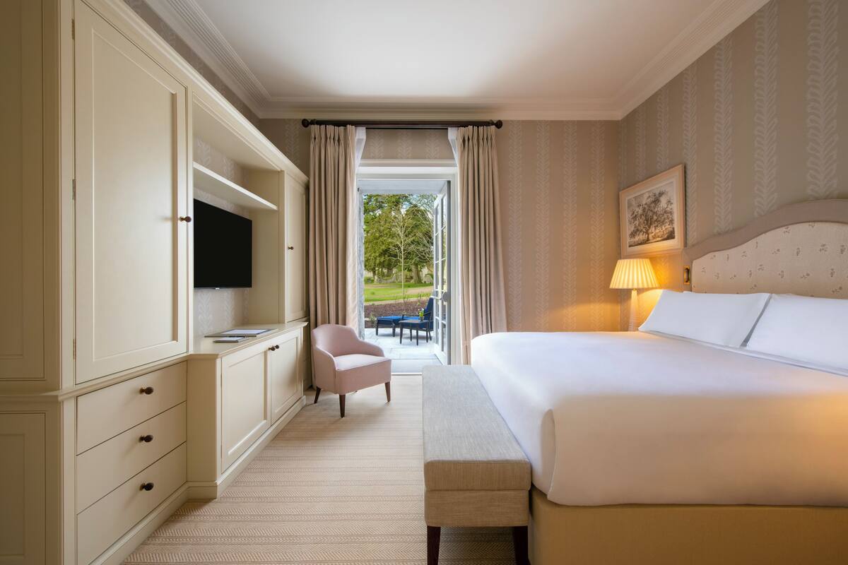 Een hotelkamer met een groot bed, een televisie, een bank, een stoel en uitzicht op de omgeving.