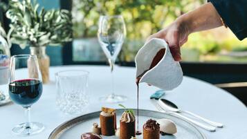 Una mesa de postres con diversos dulces y una persona sirviendo un líquido sobre un postre.