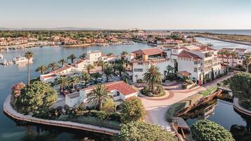 Een kustresort met een jachthaven, palmbomen en een mix van gebouwen in mediterrane stijl.