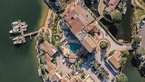 An aerial view of a waterfront property with a swimming pool, docked boats, and a parking area. - Relais et Châteaux Thalasso & Spa Ile de la Lagune (Saint-Cyprien)