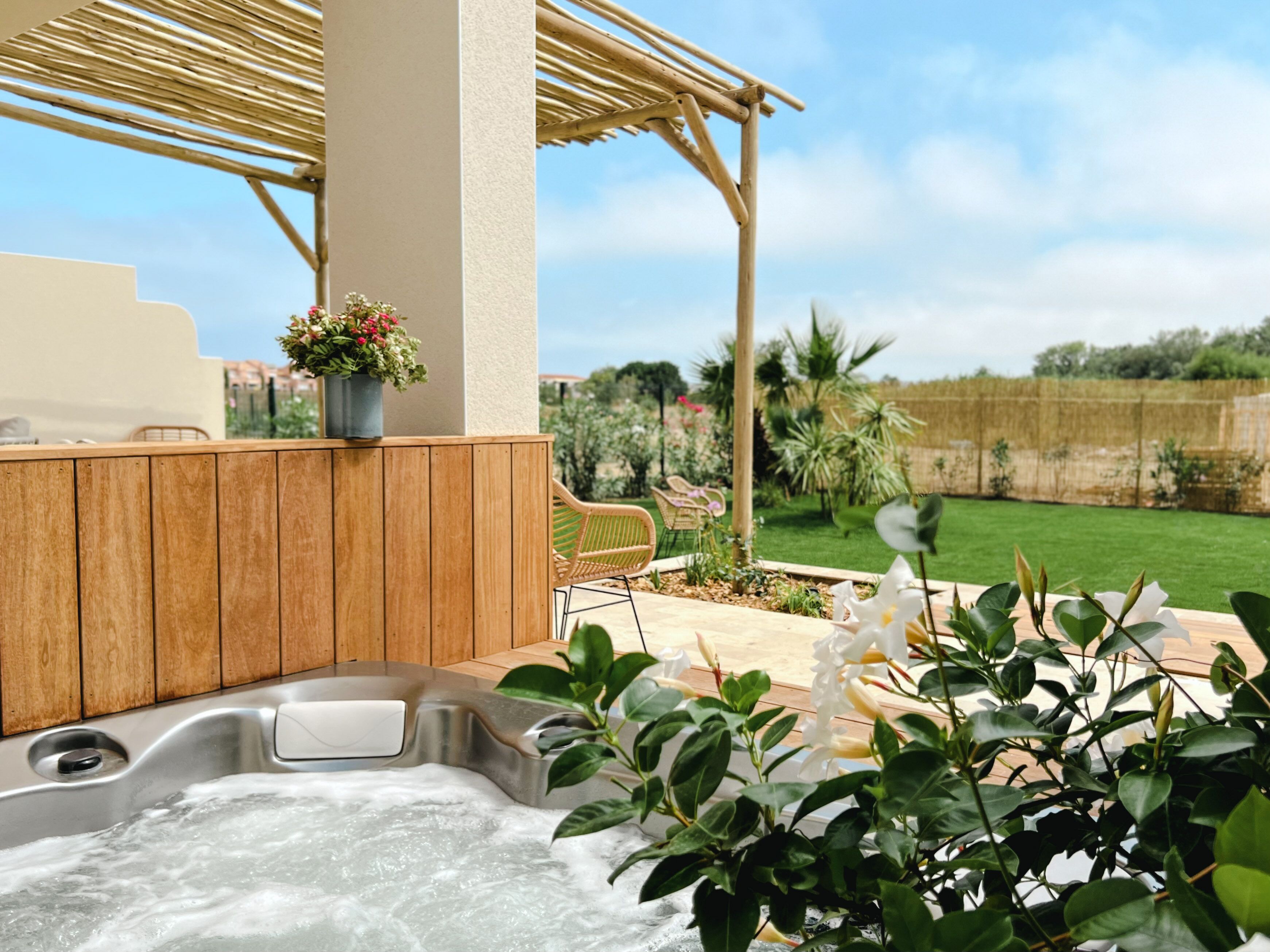 Ein Whirlpoolbereich mit Holzterrasse, einer Pergola und Blick auf den Garten.