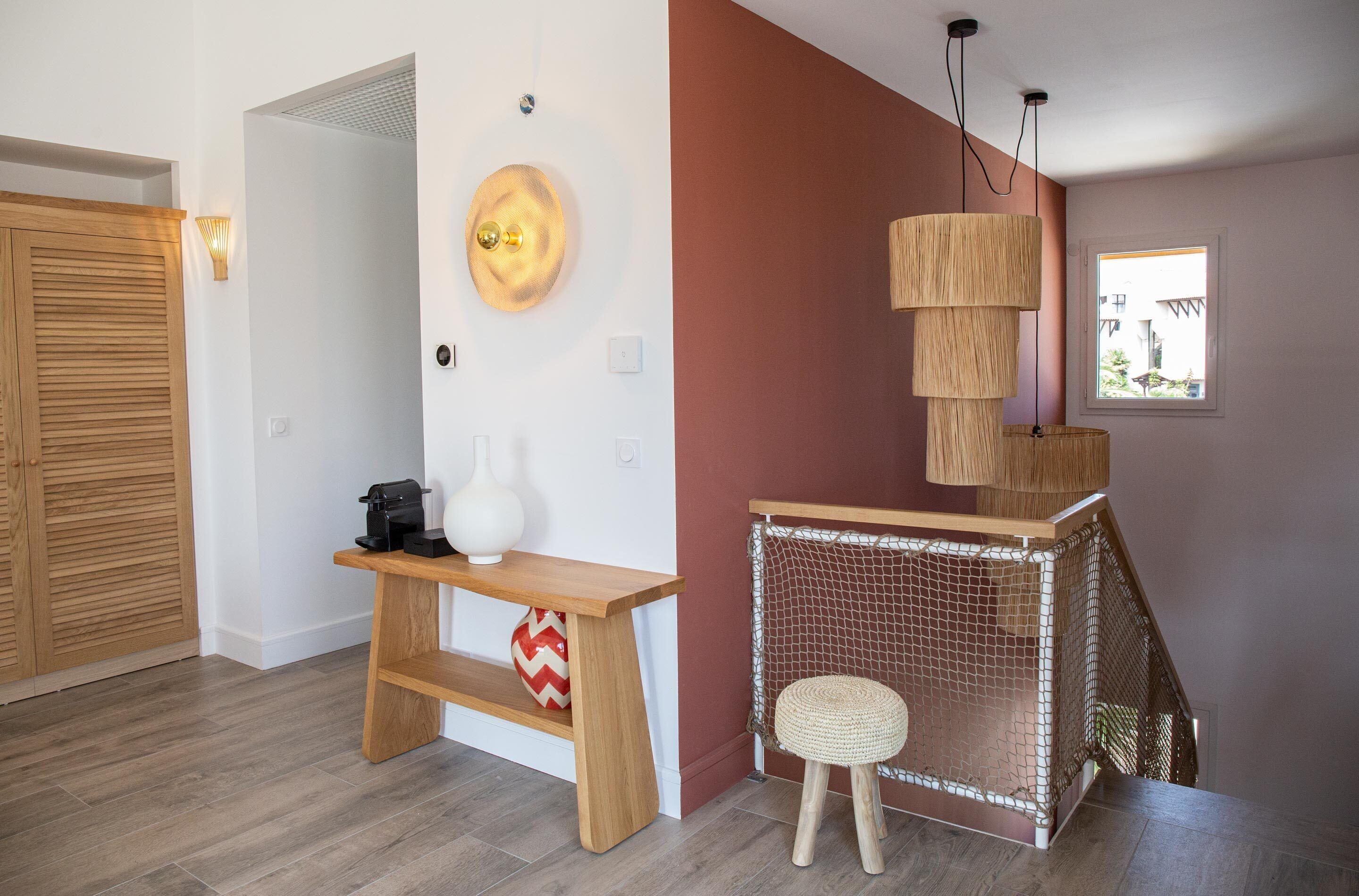 Un interior moderno con un banco de madera, un taburete pequeño, una lámpara de pared y una zona de juegos con mosquitera.