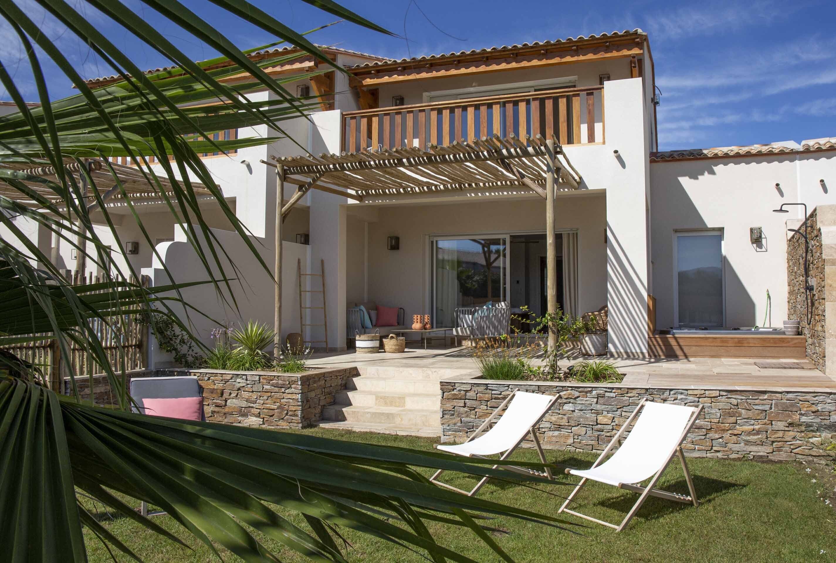 A modern house with a patio, stone walls, and a wooden pergola.