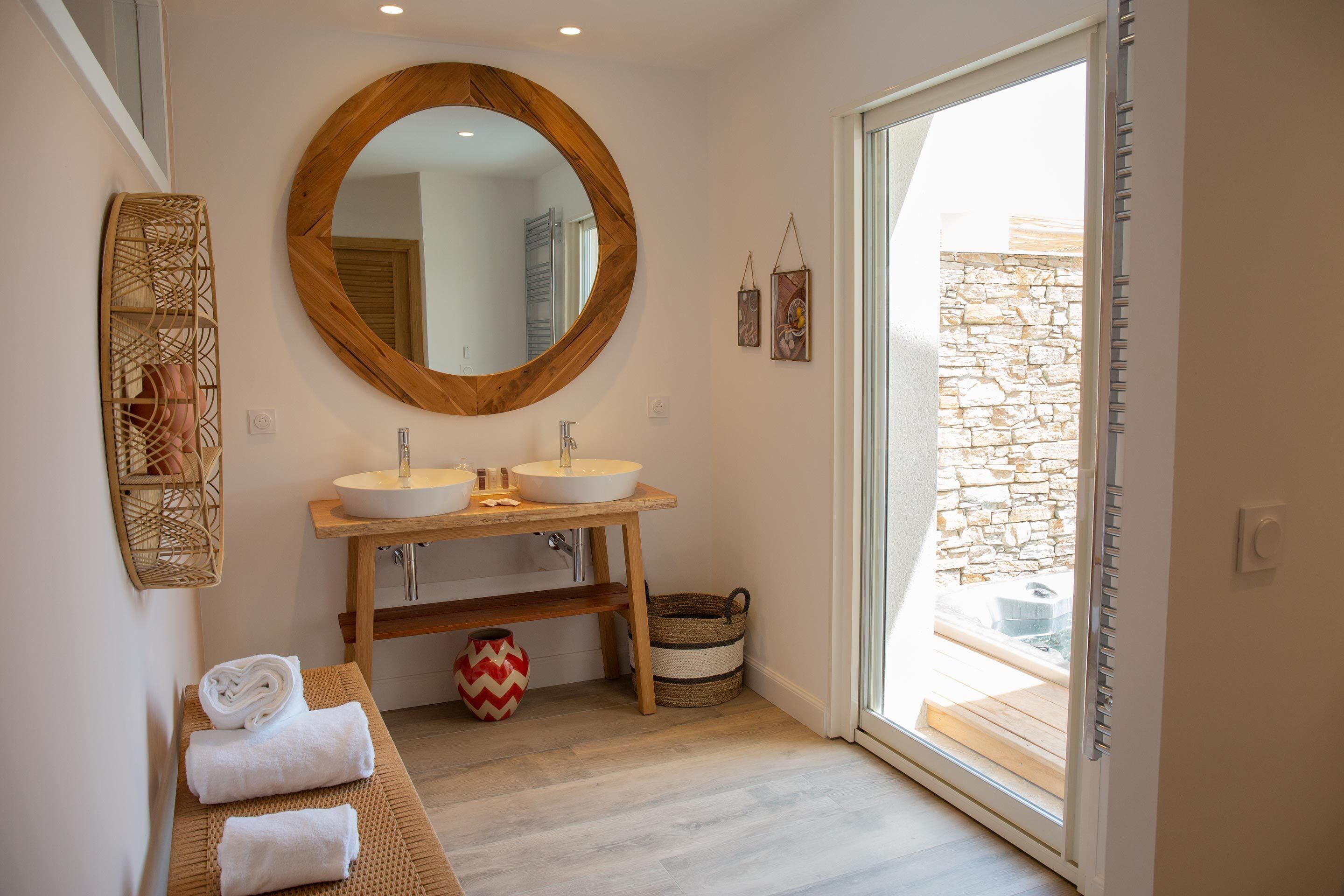 A bathroom with two sinks, a large mirror, and a bench with towels.