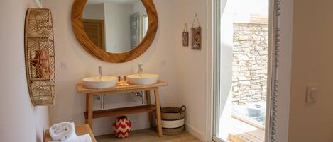 A bathroom with two sinks, a large mirror, and a bench with towels.