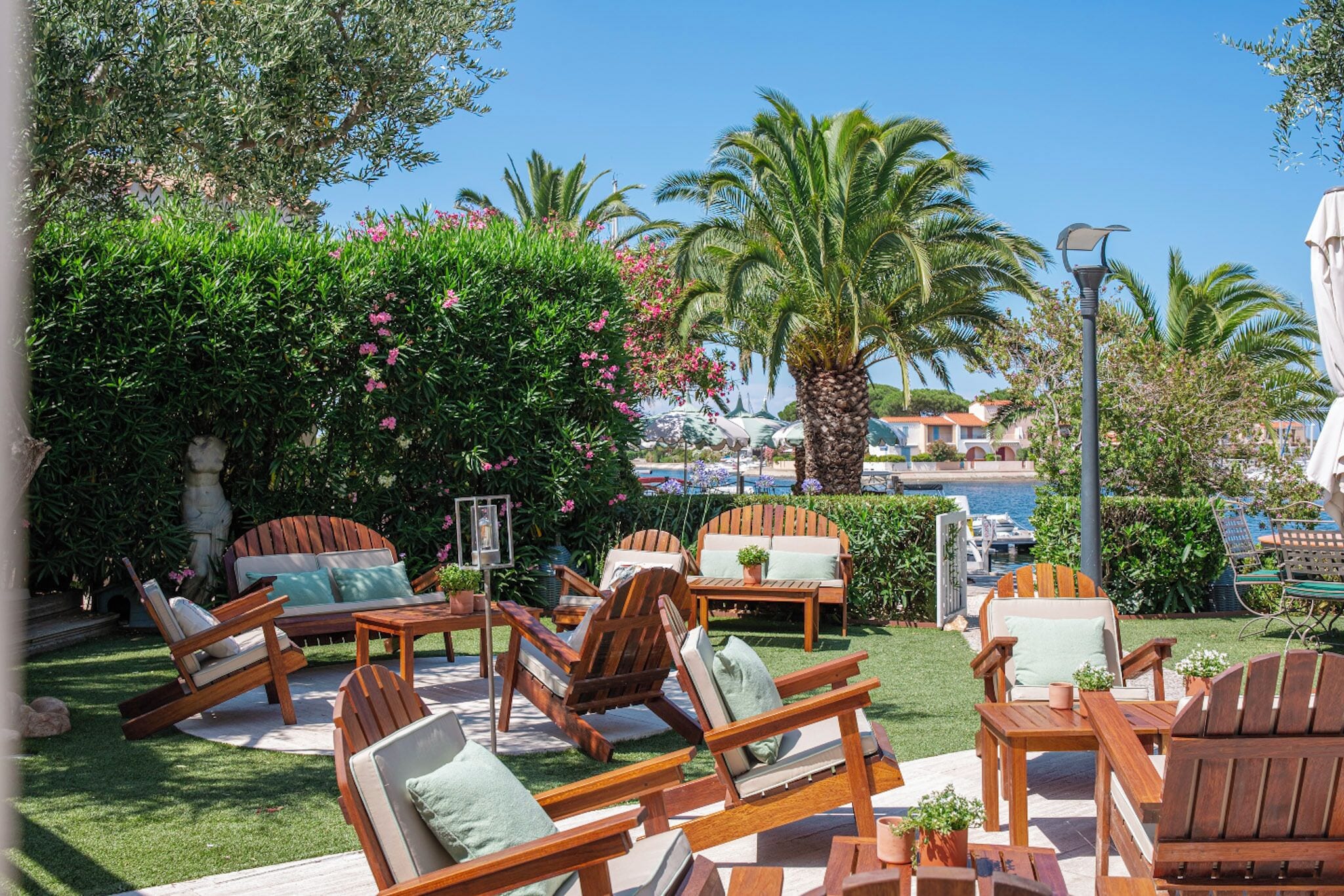 A poolside area with wooden lounge chairs, a table, and a lamp post.