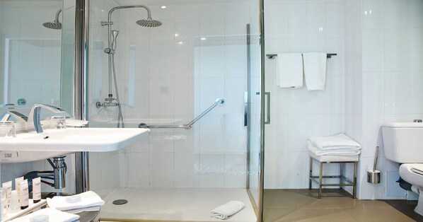 Une salle de bain moderne avec une douche à parois de verre, un lavabo avec des articles de toilette et des toilettes.