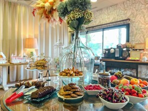 Una mesa de buffet con diversos alimentos, un florero con flores y una ventana al fondo.