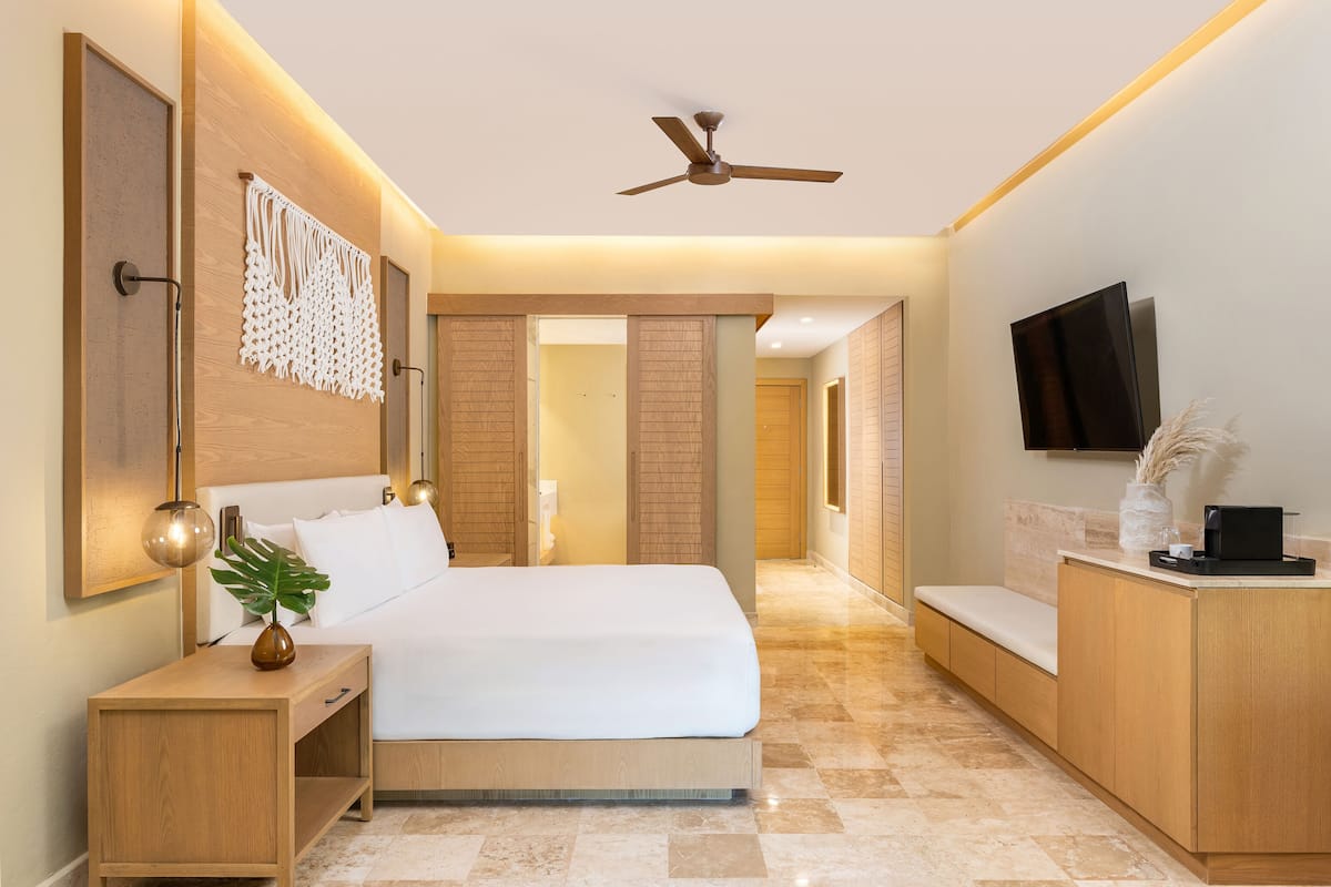 Una habitación de hotel moderna con una cama grande, una mesita de noche y un televisor de pantalla plana.
