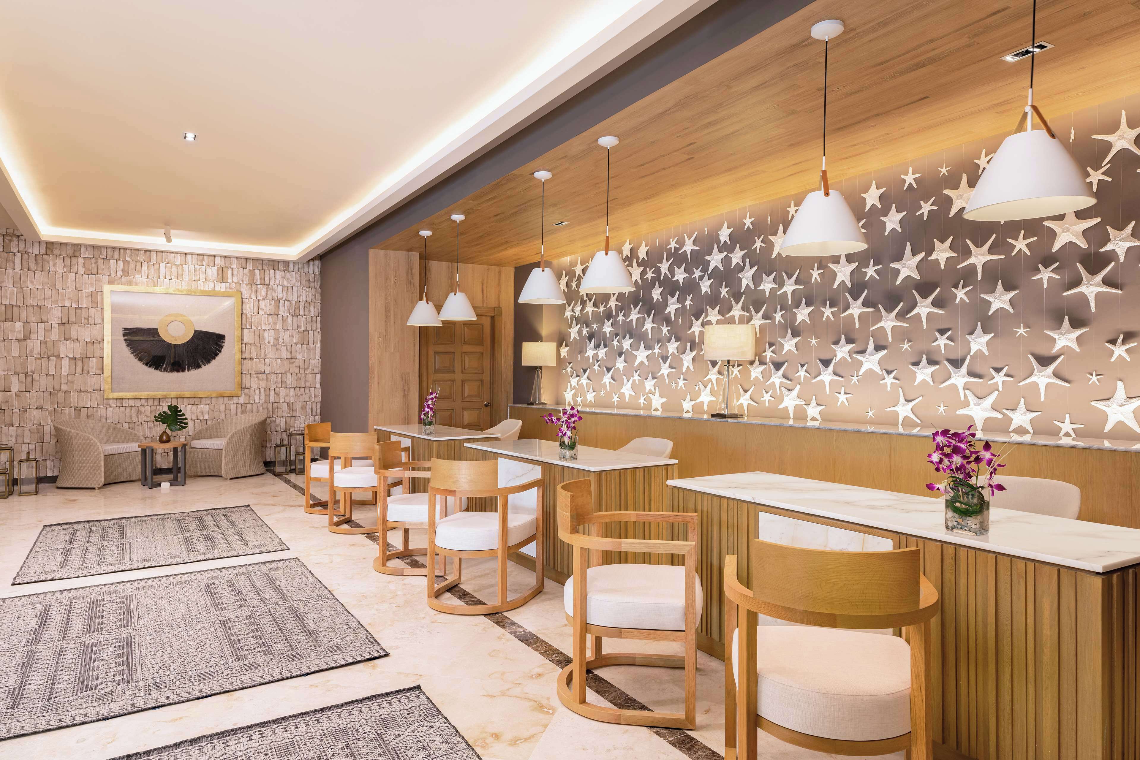 A modern reception area with wooden paneling, star-patterned wall, and white pendant lighting.