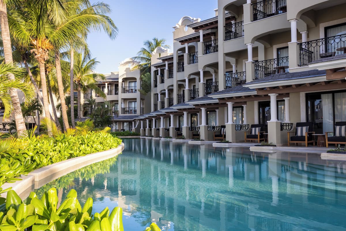 Un resort con piscina, palmeras y varios balcones.