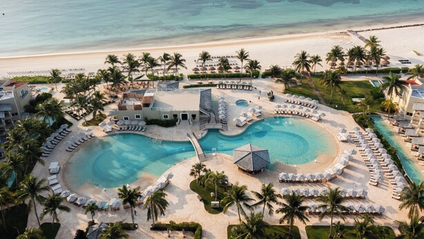 Un complexe hôtelier doté d’une grande piscine centrale, de plusieurs petites piscines et d’une zone de plage.