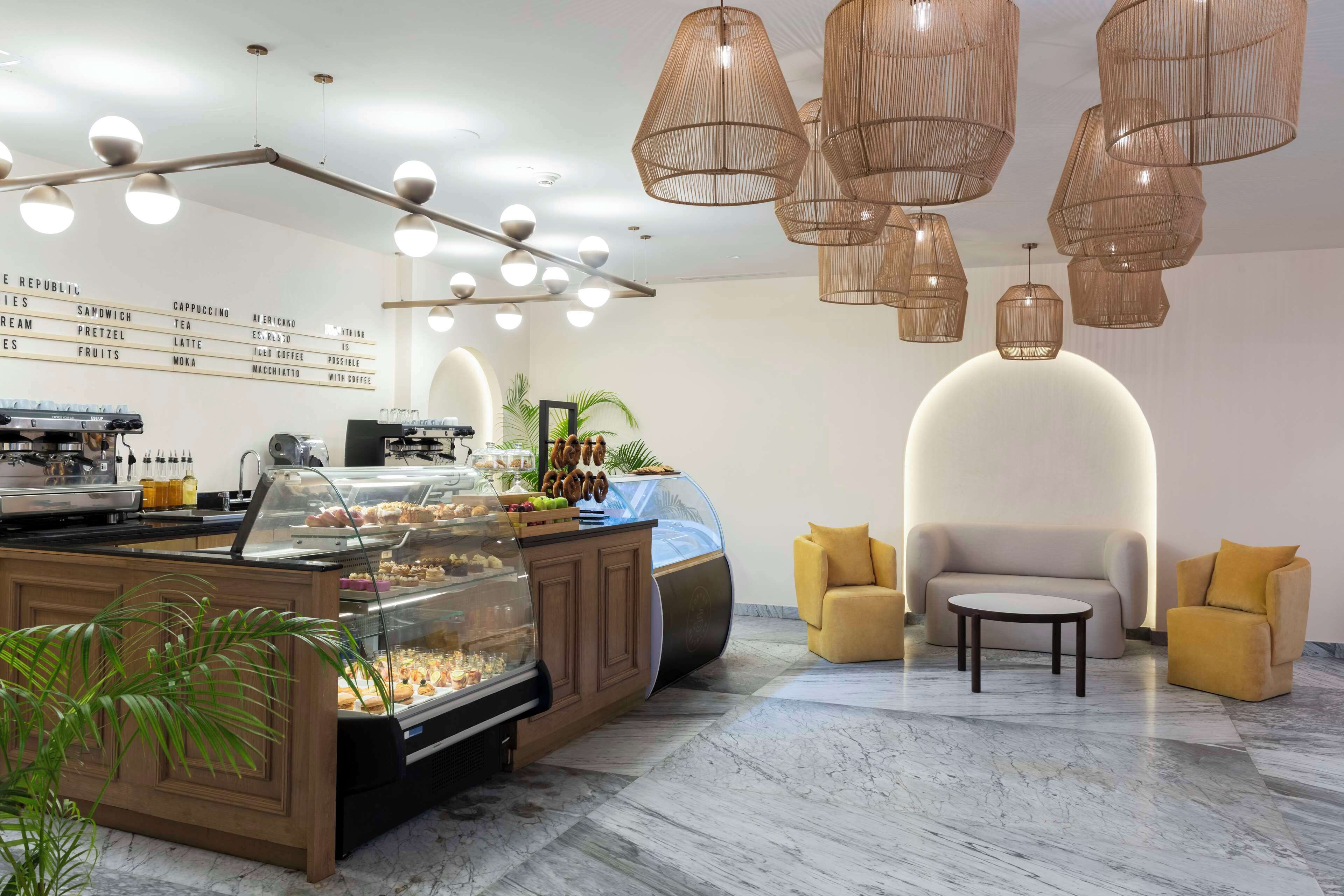 A modern cafe interior with a coffee bar, seating area, and a menu board.
