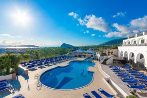 Una piscina techada, una piscina al aire libre, sombrillas