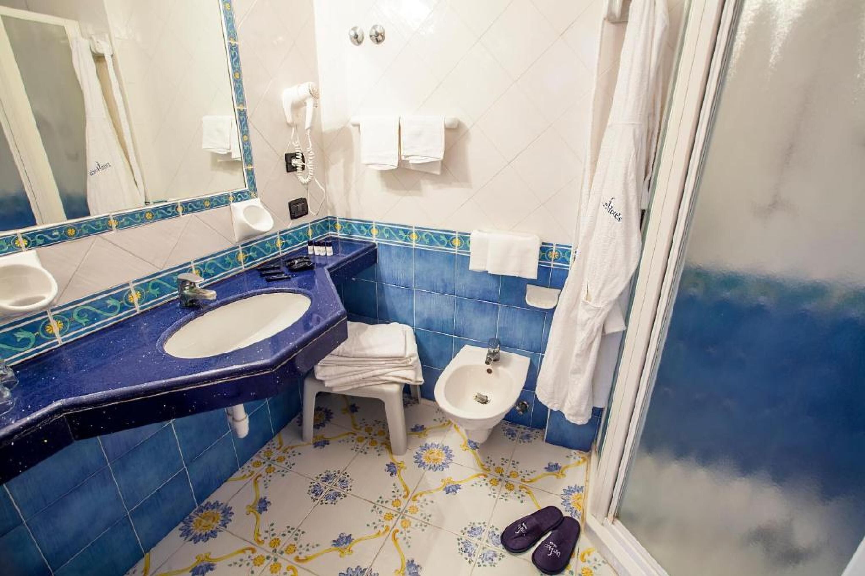 A bathroom with a sink, bidet, and shower.